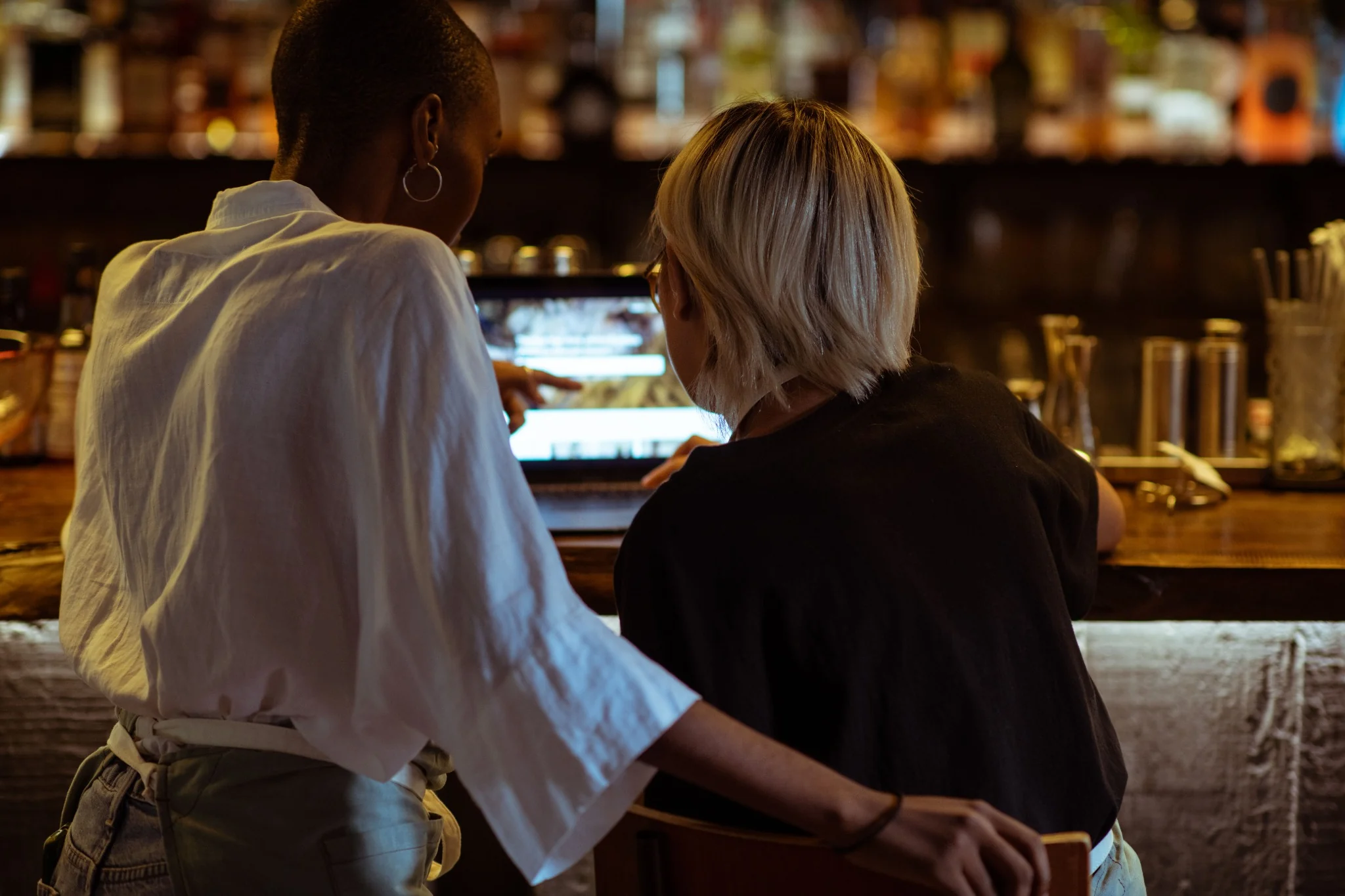 A staff member showing something on a laptop to a customer at a counter.