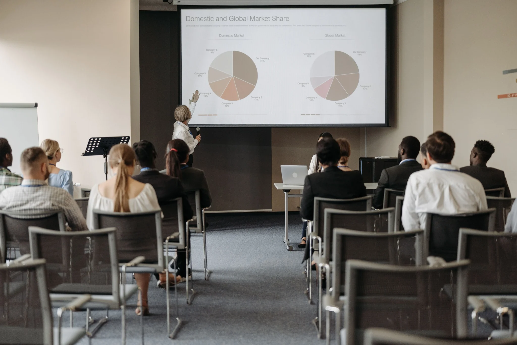 A presenter speaking to an audience in a conference room.