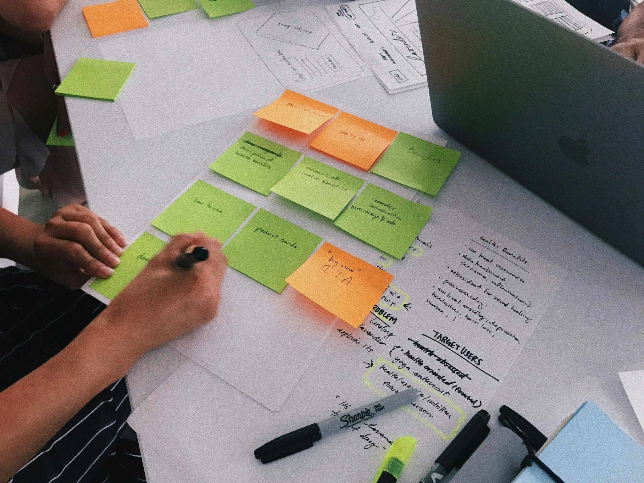 Hands sorting and annotating sticky notes during a research session.